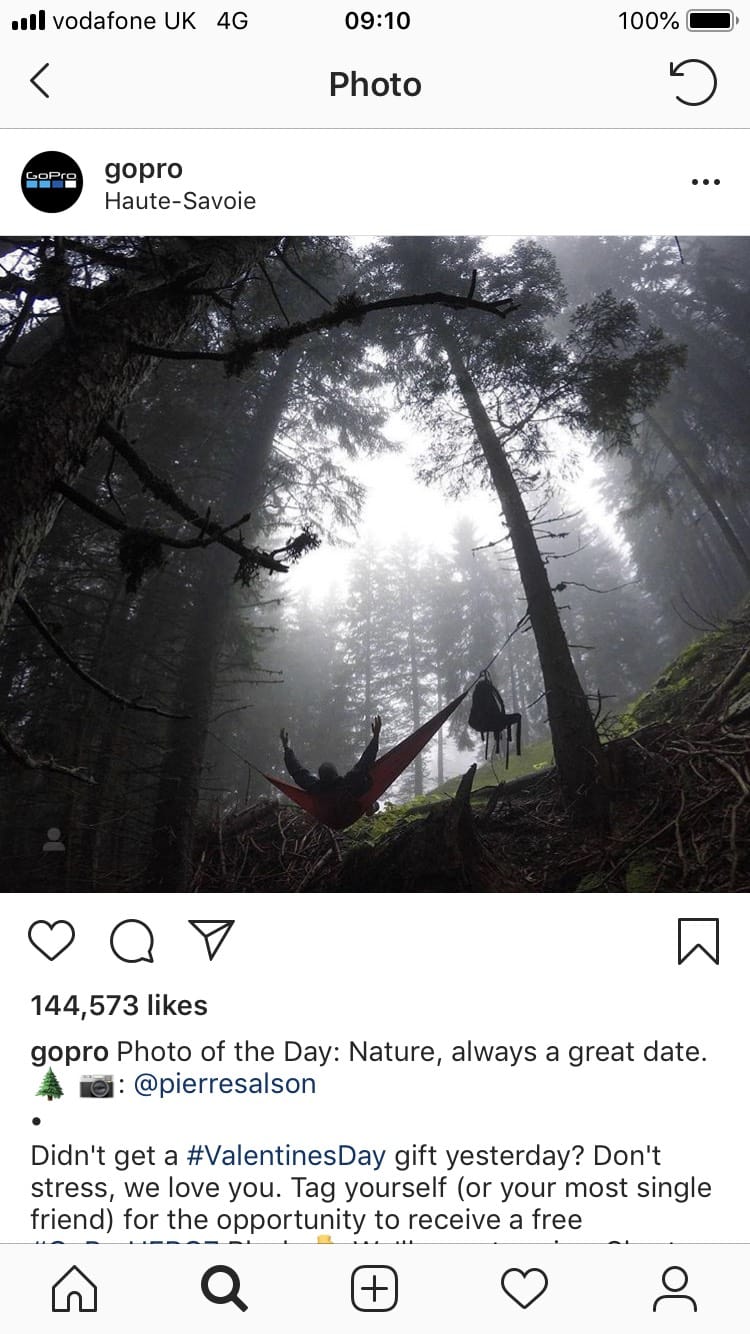 Screen shot of the GoPro Instagram feed — a person lies in a hammock in darkening forest with arms open to the sky