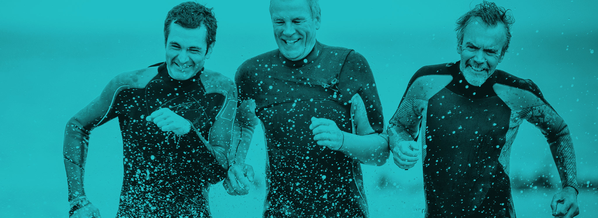 Rebrand - Peak Wellbeing - 3 men in wetsuits run through surf
